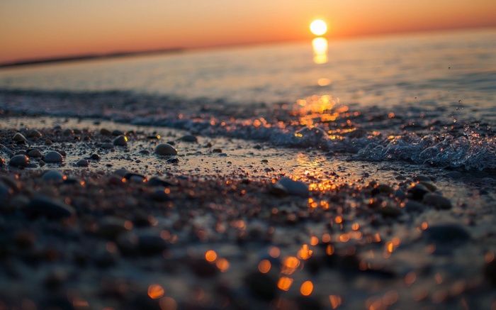 Sunset over a pebble beach with gentle waves
