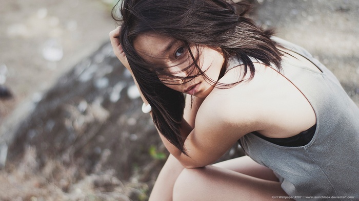 Asian woman with dark hair sitting outdoors