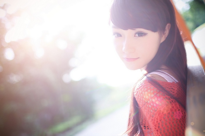 Asian woman with brunette hair wearing an orange top