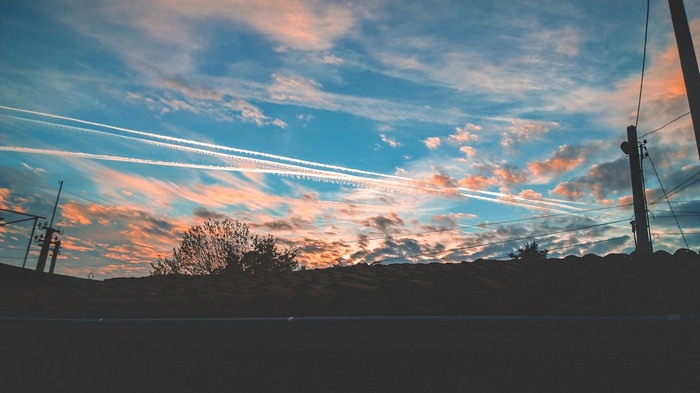 Sunset sky with contrails over rooftops