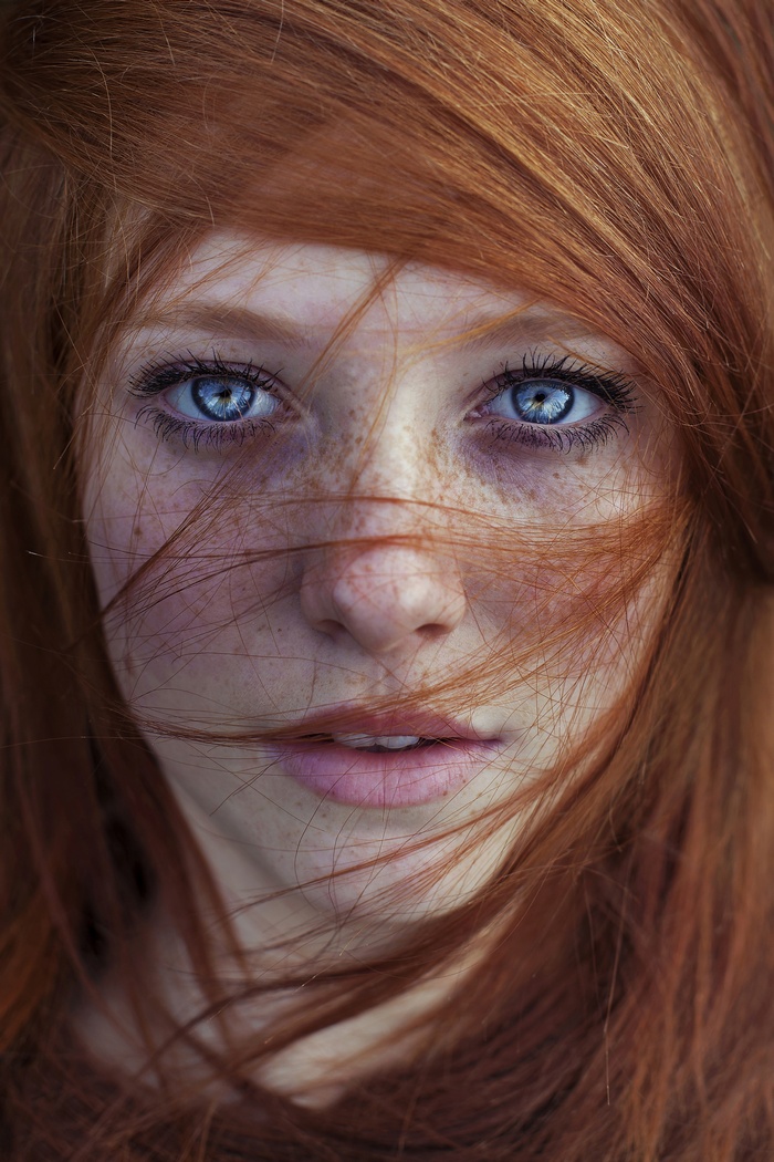 Close-up portrait of a young redhead woman with blue eyes and freckles