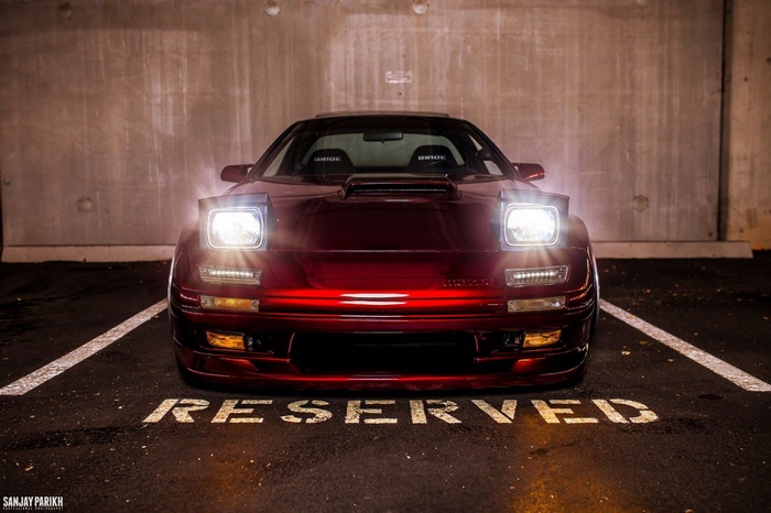Red Mazda RX-7 with pop-up headlights in a parking spot