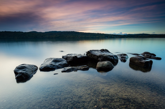 Rocks in a calm lake at sunset