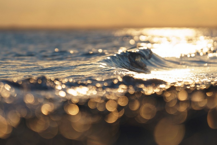 Golden hour waves on the sea horizon with bokeh