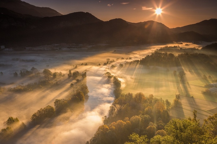 Sunrise over a misty valley with sun rays
