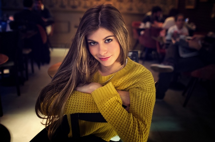 Woman with long wavy hair wearing a yellow sweater