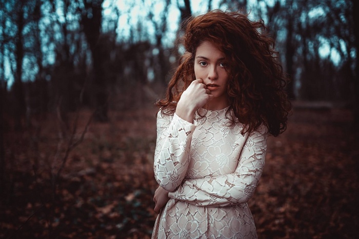 Woman with red hair in a white dress in a forest