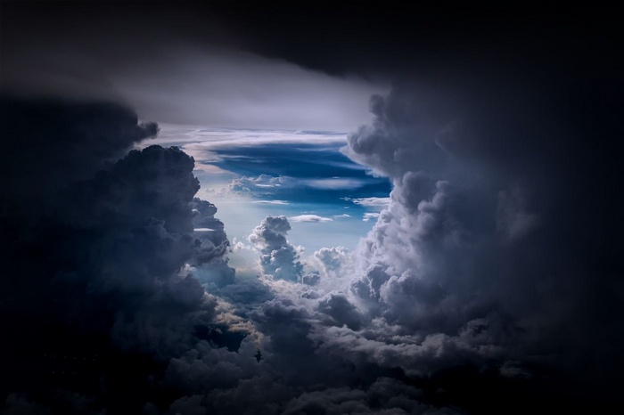 Dramatic view through dark storm clouds to a bright sky