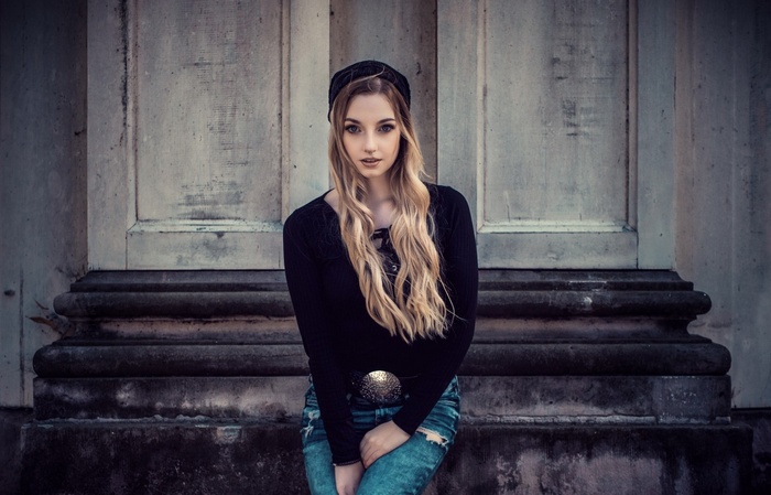 Woman with long blonde hair wearing a black top and jeans