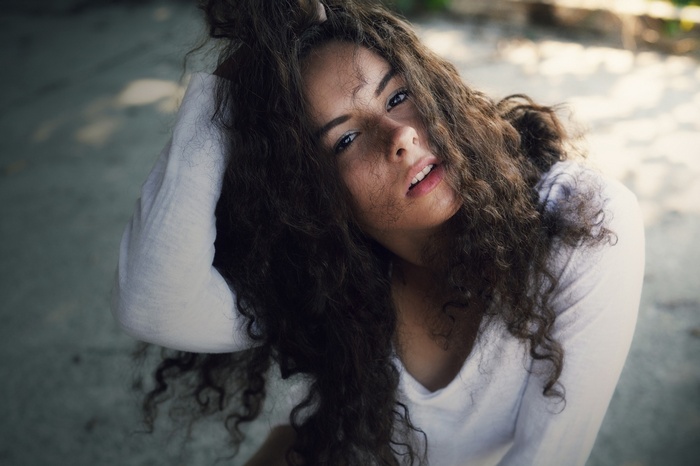 Woman with curly dark hair in white clothing