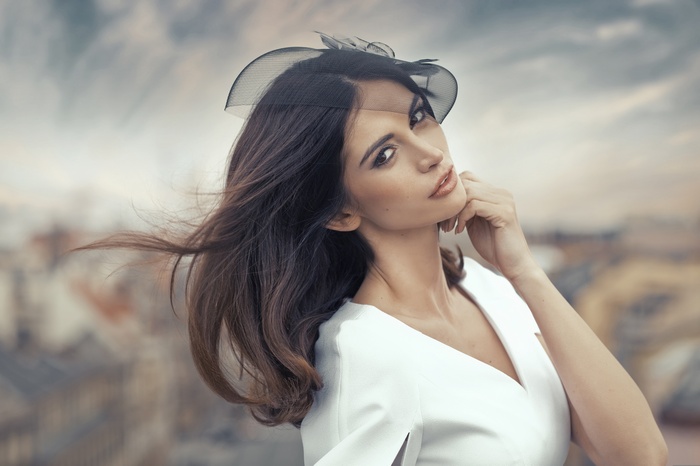 Woman in white dress wearing a black fascinator