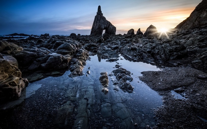 Rocky coastline with natural arch at sunset
