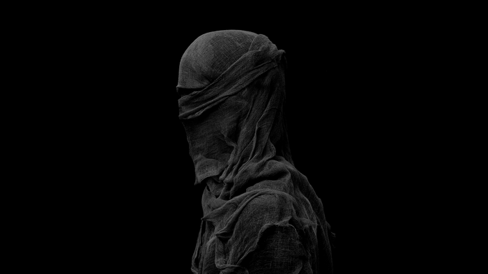 Figure covered in dark cloth against black background