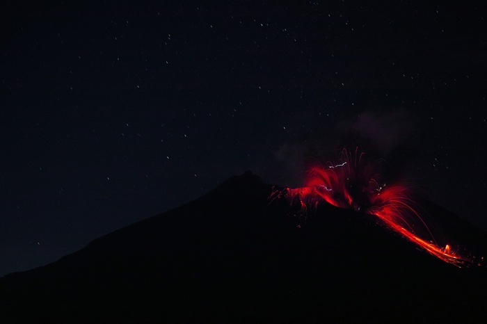 Volcano eruption at night with stars
