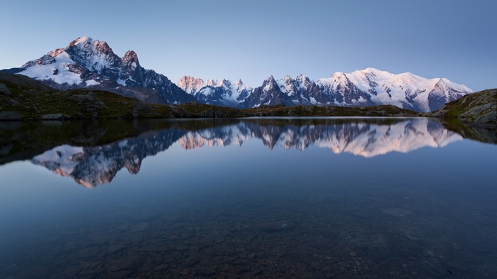 Snow-capped mountains reflected in a calm lake at sunrise