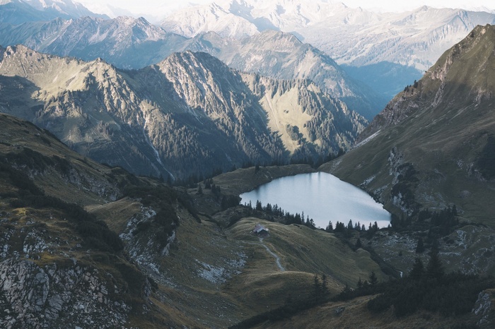 Lake nestled in a mountain valley with a small cabin
