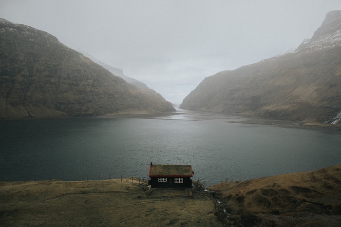 A remote cabin by a lake in a misty mountain landscape