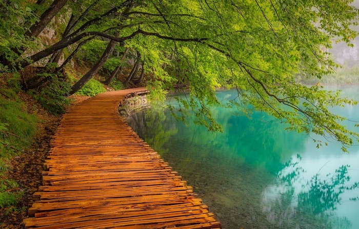 Wooden walkway along a turquoise lake in Plitvice National Park