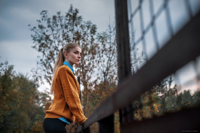 Woman with blonde ponytail in an orange sweater outdoors