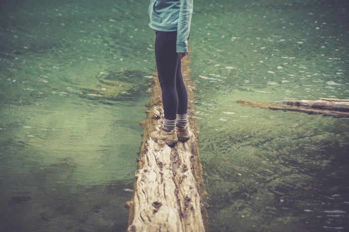 Person balancing on a log over water