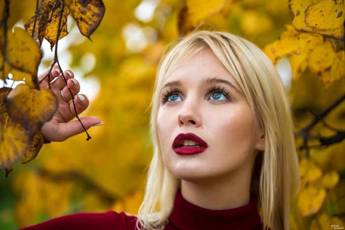 Woman with blonde hair and blue eyes in autumn leaves