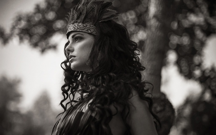 Woman with feathers in her hair looking away