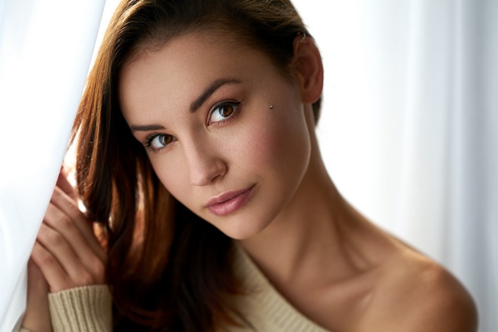 Woman with piercing posing near curtain
