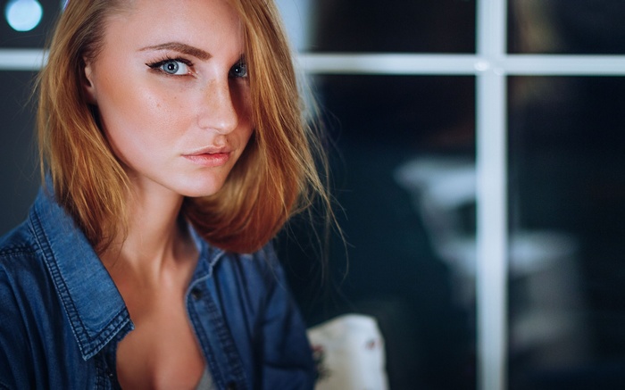 Margarita Zeziulia in a denim shirt by the window