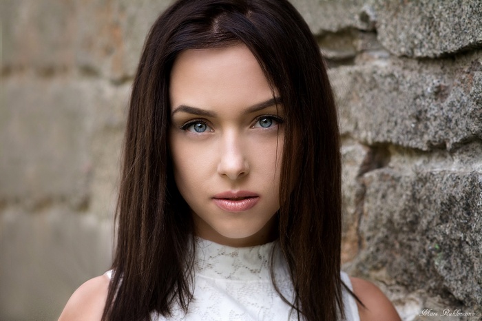 Woman with blue eyes in front of a stone wall
