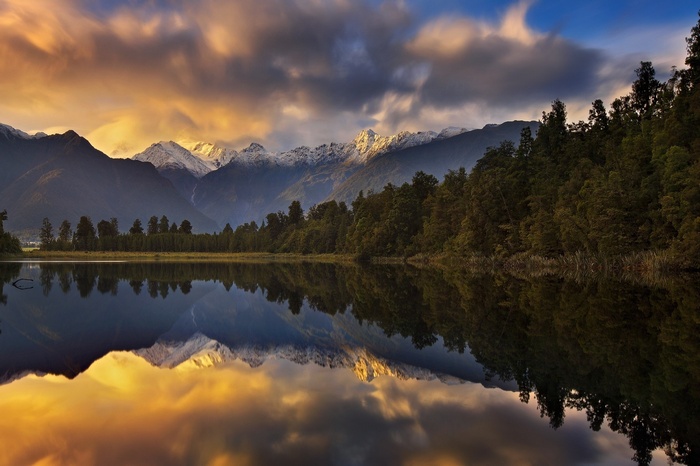 Lake Matheson with snow-capped mountains and forest reflection