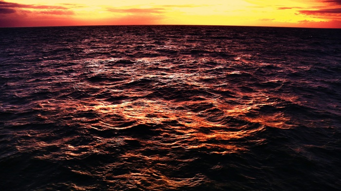 Sunset over the ocean with choppy waves