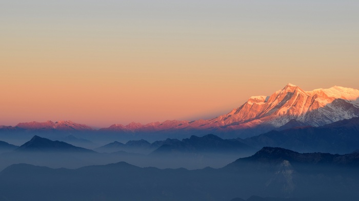 Snow-capped mountains at sunrise with mist