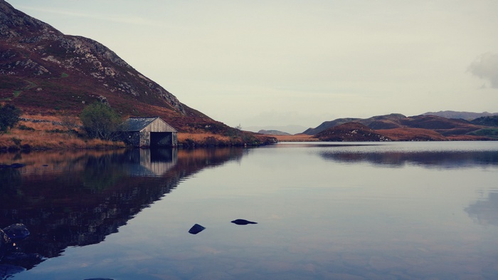 Boathouse on a lake with mountains in the background