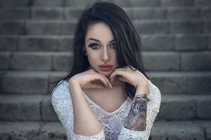 Woman with tattoos and piercings sitting on stairs