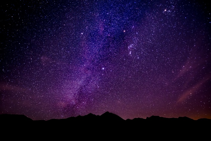Night sky with stars and the Milky Way over mountains