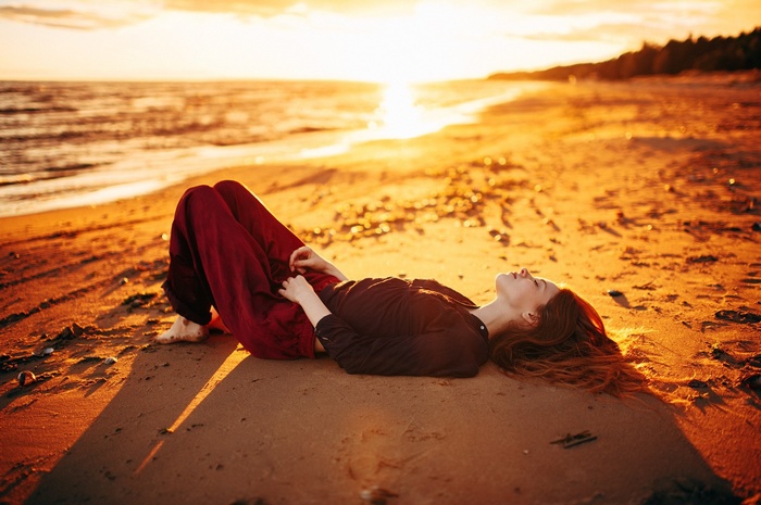 Woman lying on a beach at sunset