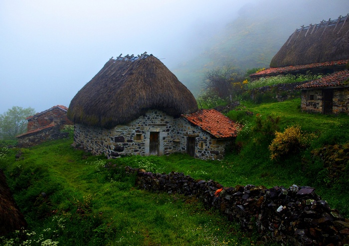Stone houses with thatched roofs in the mist