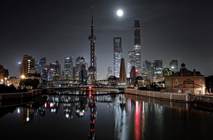 Shanghai skyline at night with moon and river