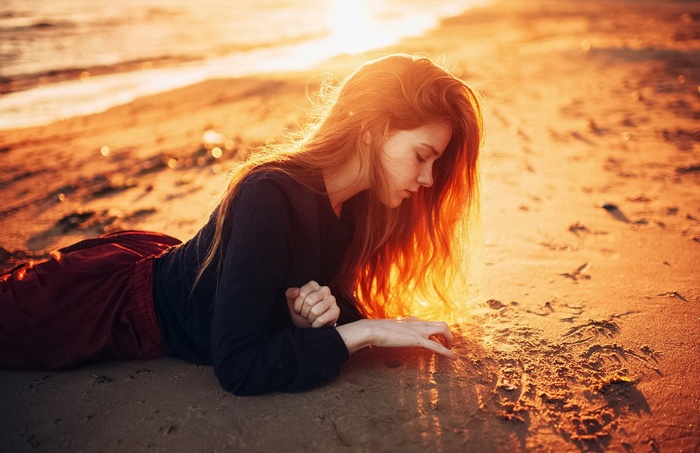Woman lying on a beach at sunset