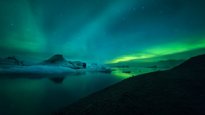 Aurora Borealis over icebergs on a lake at night