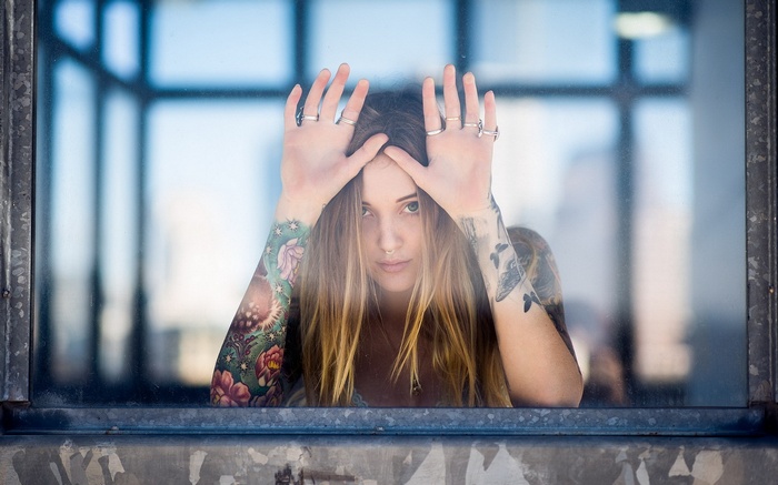 Woman with tattoos looking through a window