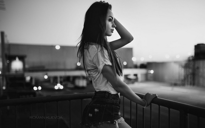 Woman in jean shorts on balcony at night