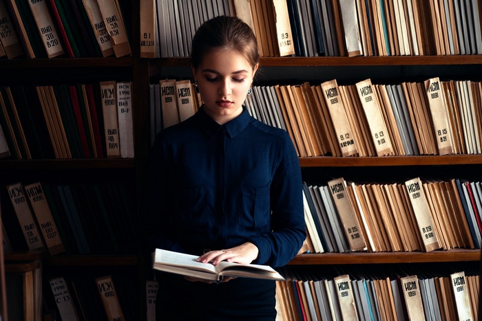 Young woman reading a book in a library