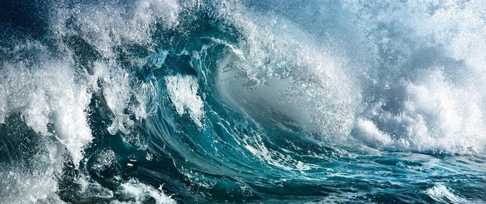 A powerful ocean wave crashes with white foam