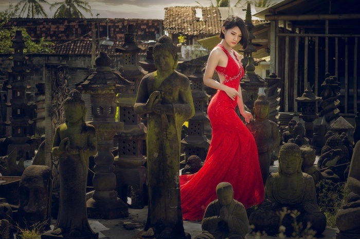 Asian model in red dress among Buddha statues
