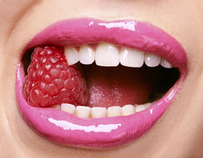 Close-up of lips with raspberry and teeth