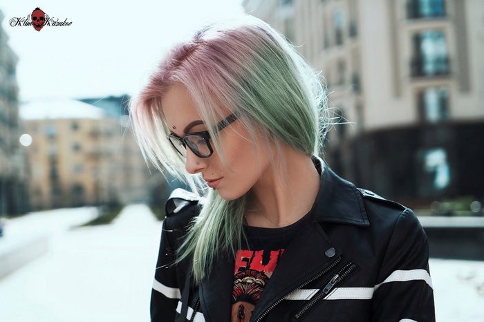 Sasha Brink with dyed hair and glasses in a city