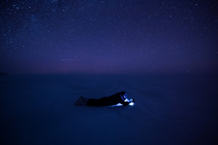 Person lying on snow under starry sky at Concordia Research Station