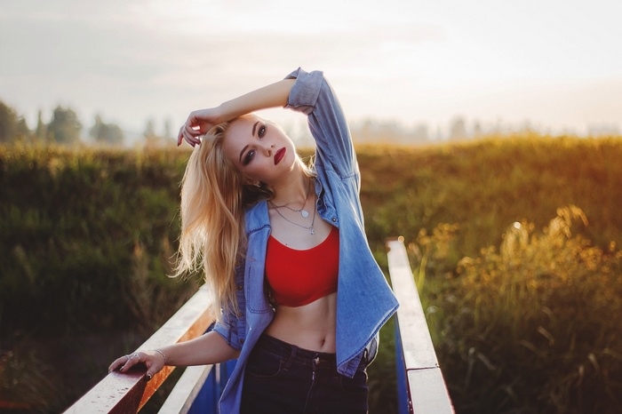 Woman in denim shirt and red top on a bridge