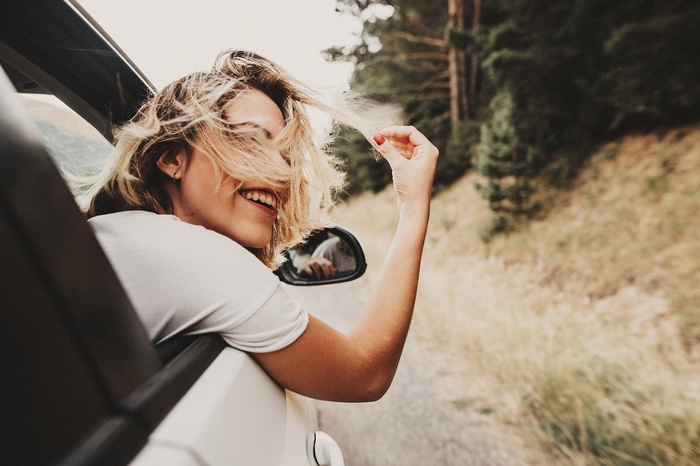 Woman with blonde hair smiling in a car